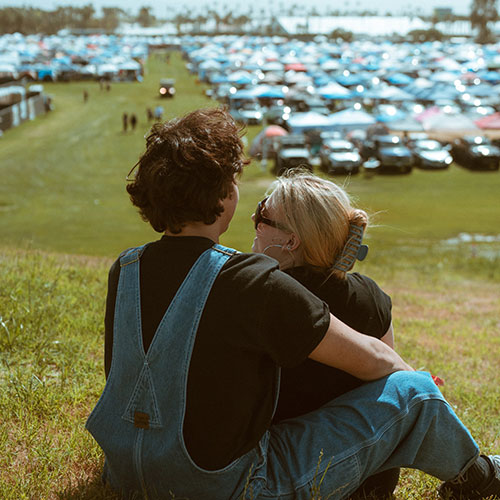 Two Coachella fans sitting on grass