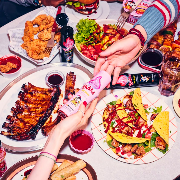 Bottle of Buldak over table with plates of food