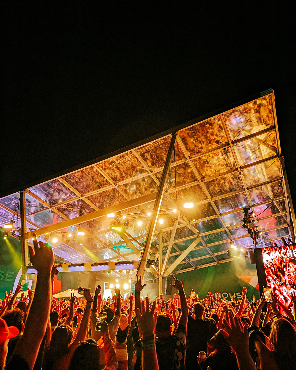 Photo of fans with hands in air in front of stage