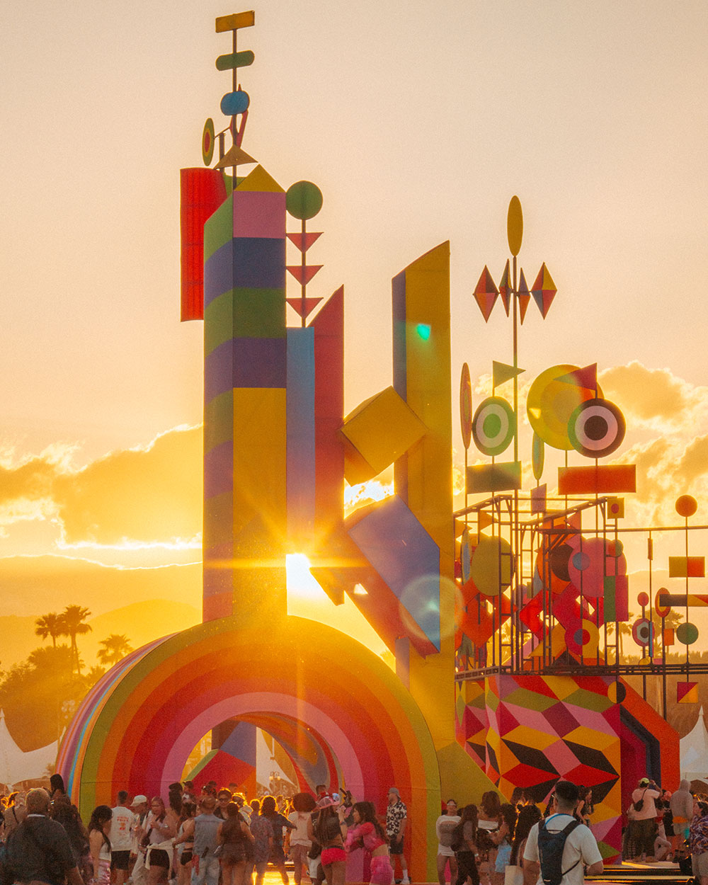 Photo of festivalgoers in front of art installation at sunset