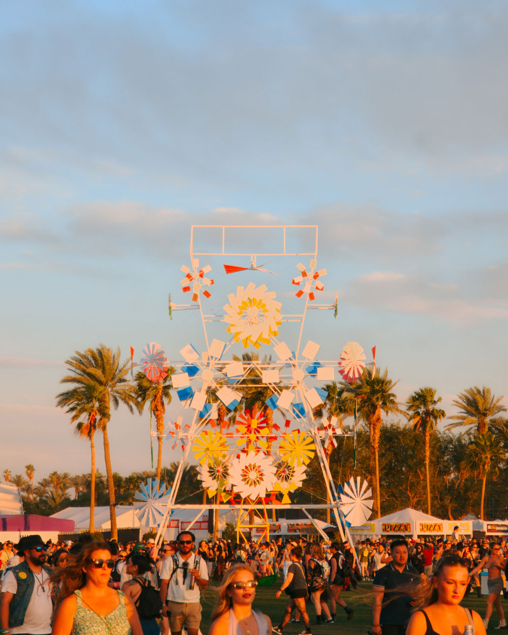 fans walking in front of art installation at sunset