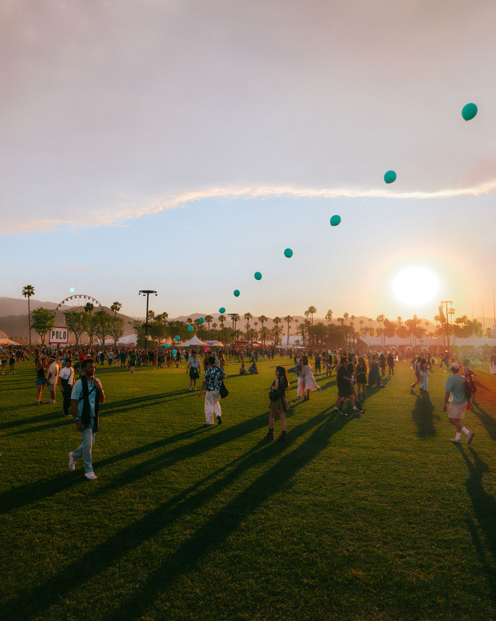 fans walk across field in front of balloon chain at dusk