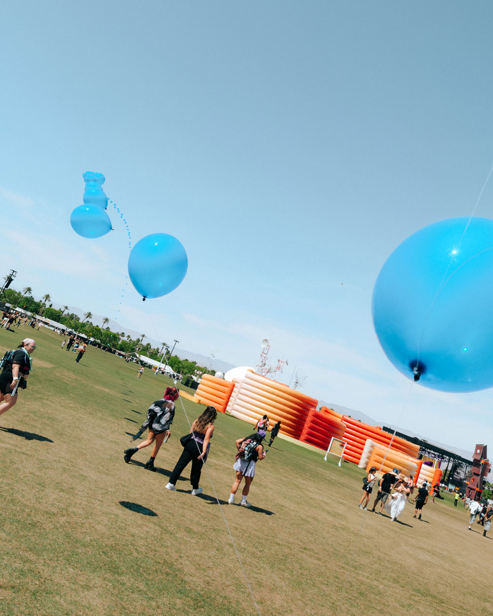 fans walking across green grass under balloons
